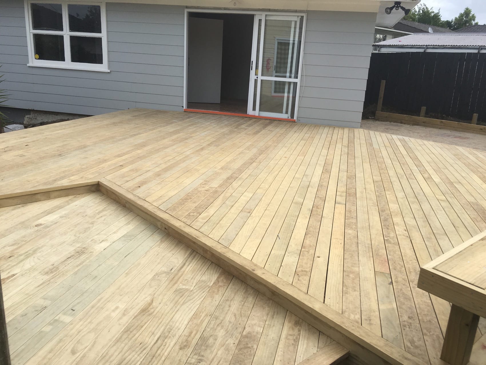 A finished timber deck wrapping the rear of a weatherboard house with a built-in seat.