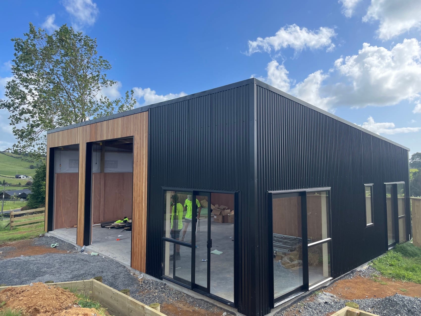 The same standalone building seen from the side, showing the dark cladding and roof line.