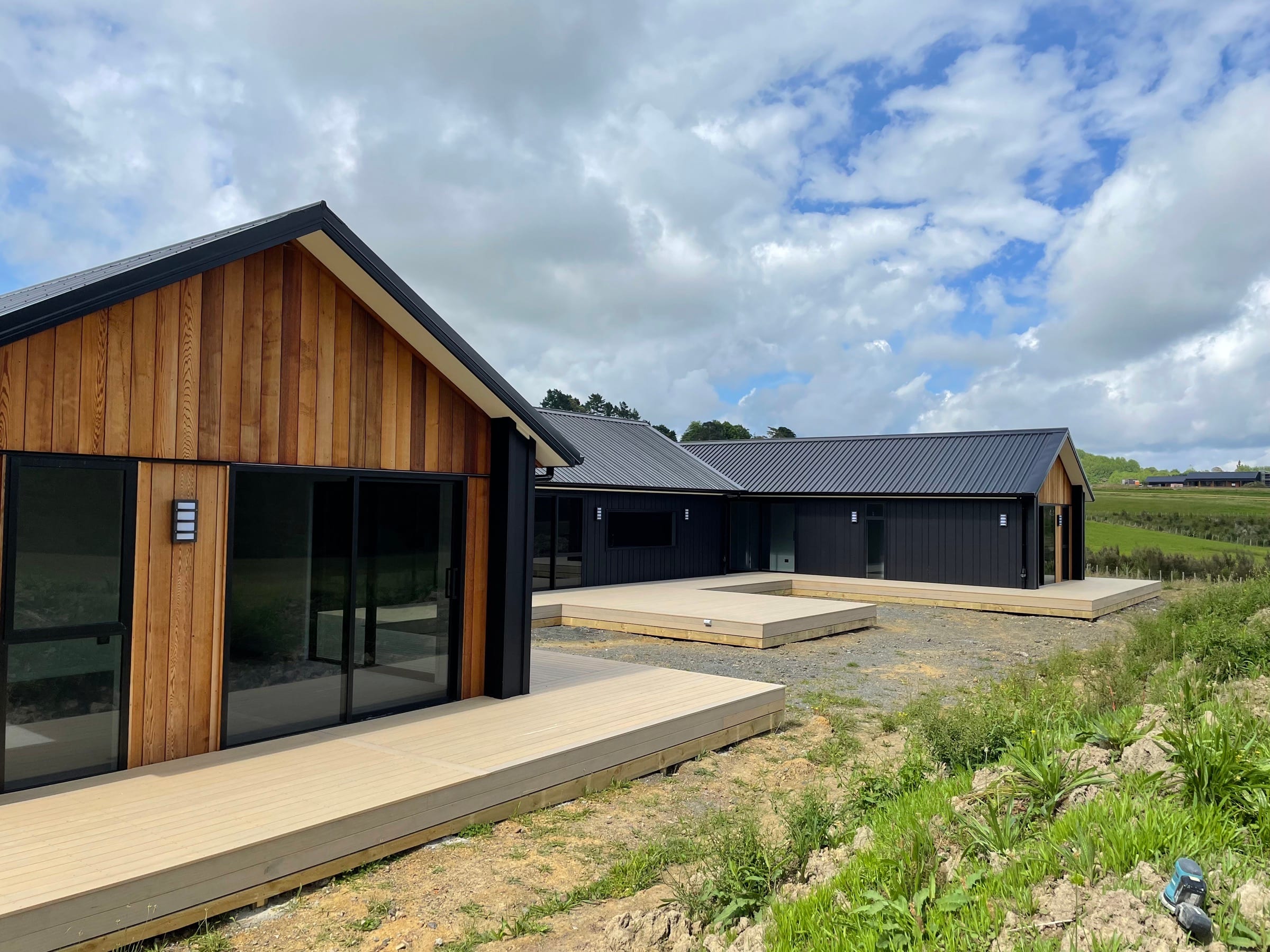 A home built by Backline Construction: a gable end clad in vertical cedar, with dark board cladding and a full-width deck.