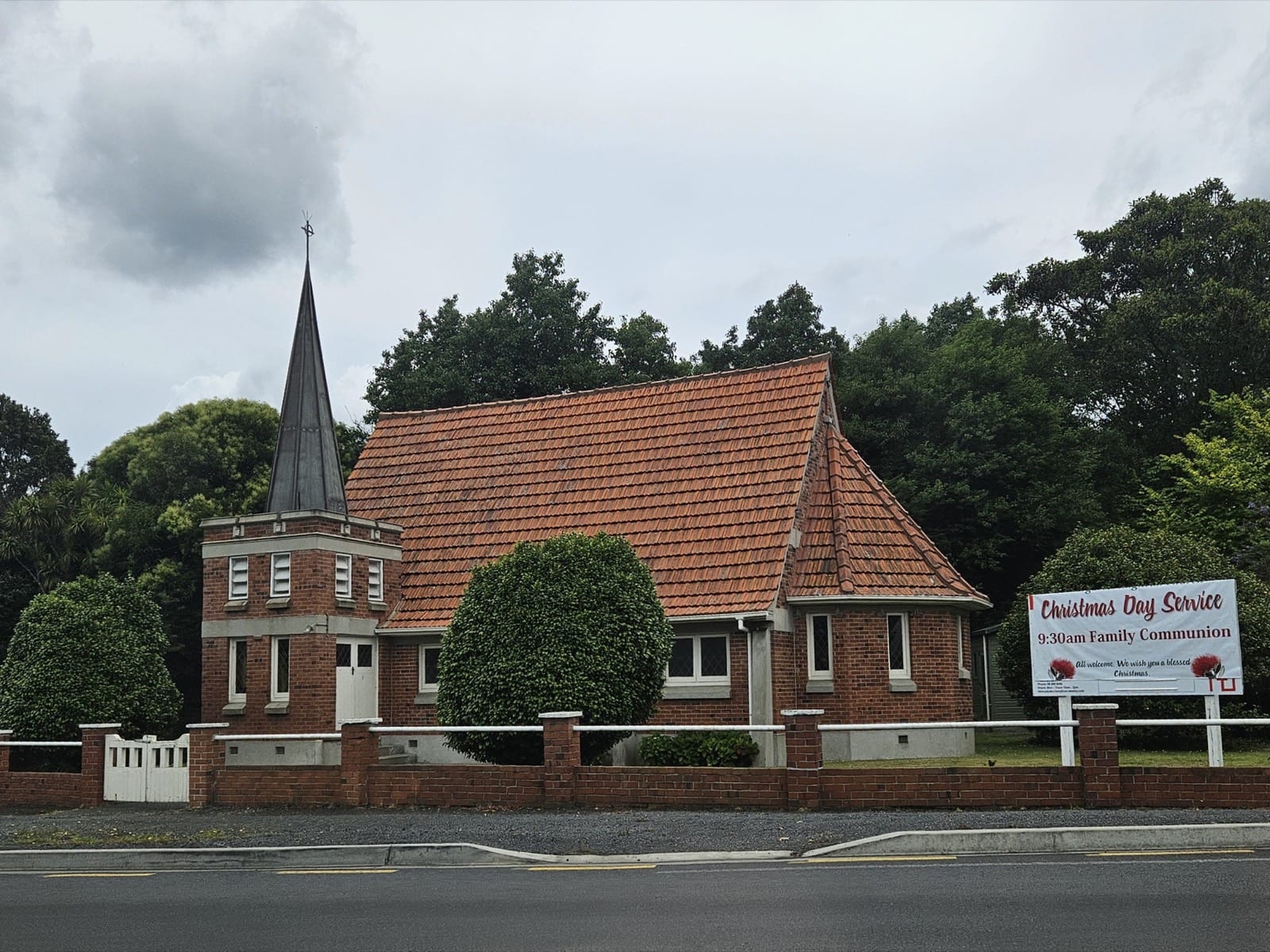 St Margaret's brick church with its spire behind a low brick wall at Karaka.