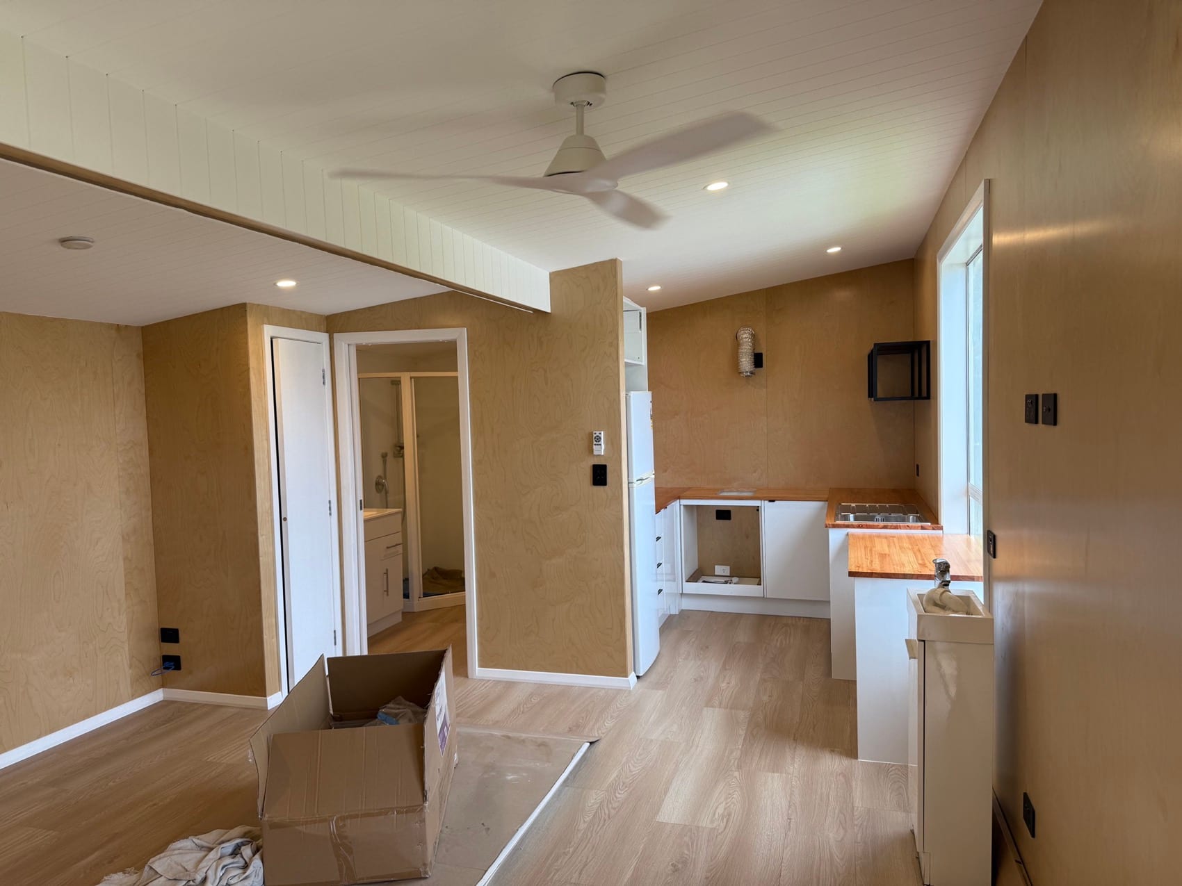 The view down a hallway of a Backline fit-out towards the new kitchen, flooring laid and trims on.