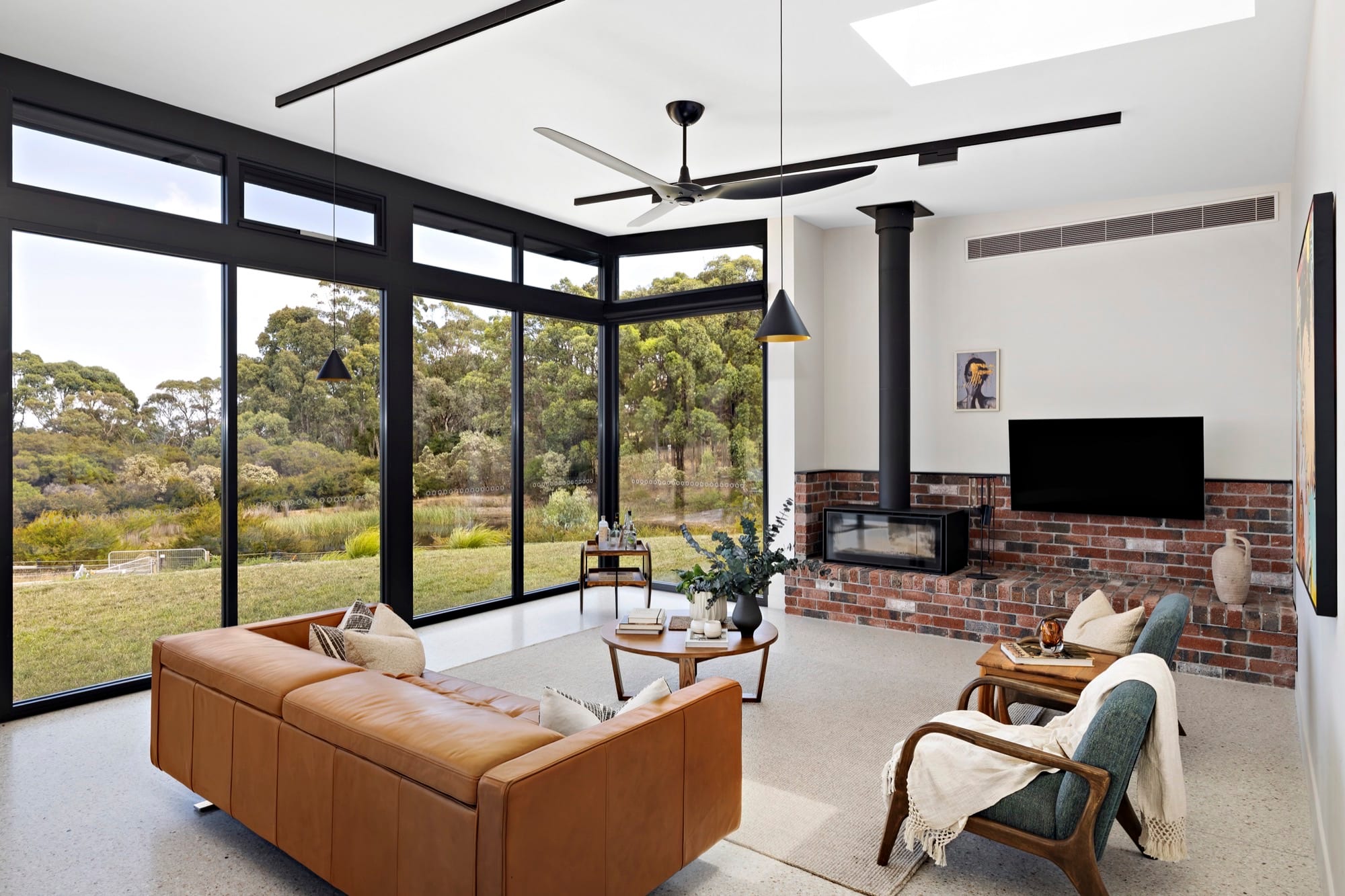 A living space with exposed brickwork, tan leather seating and a timber-lined ceiling.
