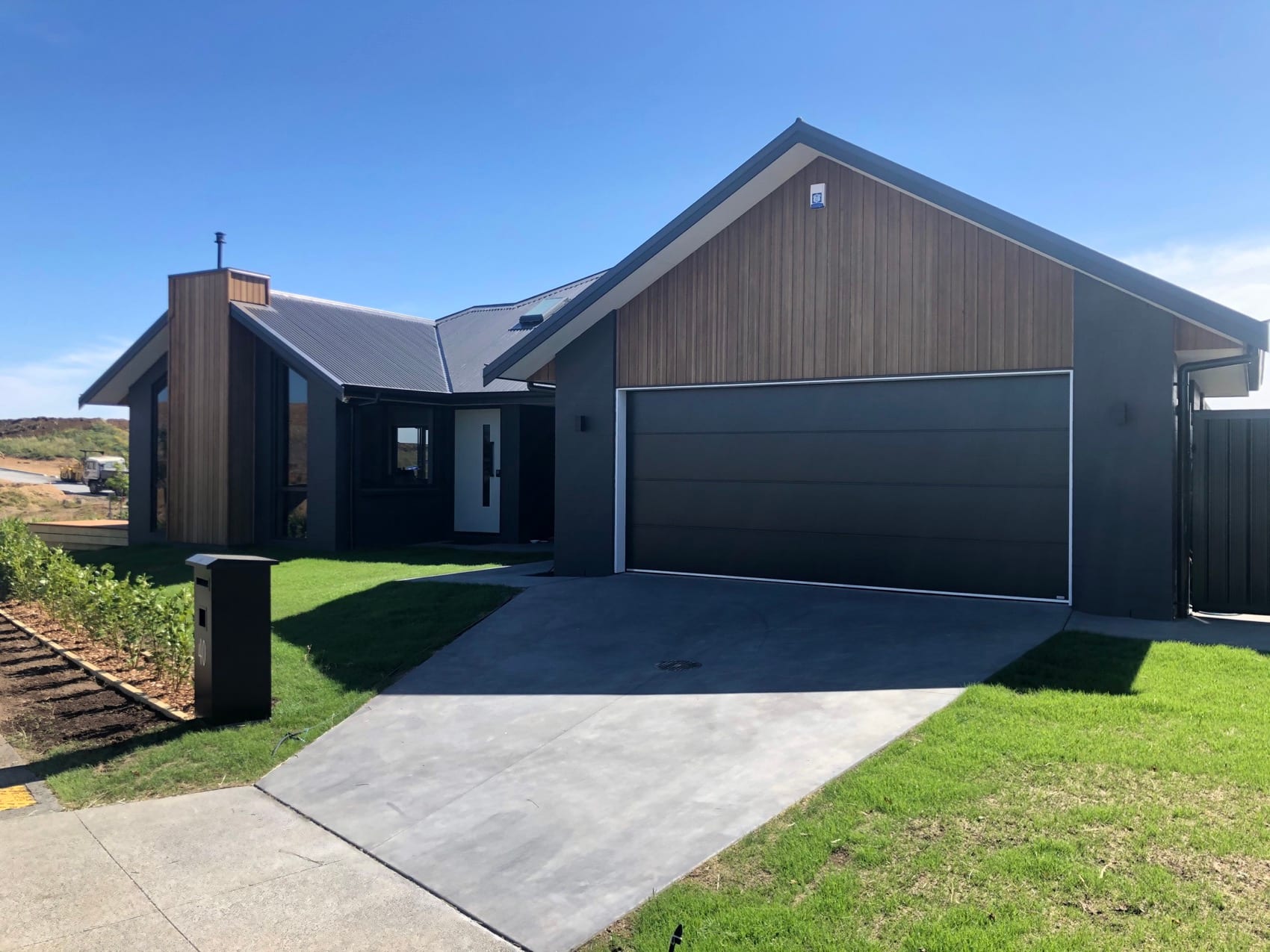 A completed Backline Construction new build with cedar and dark board cladding, double garage and finished driveway.