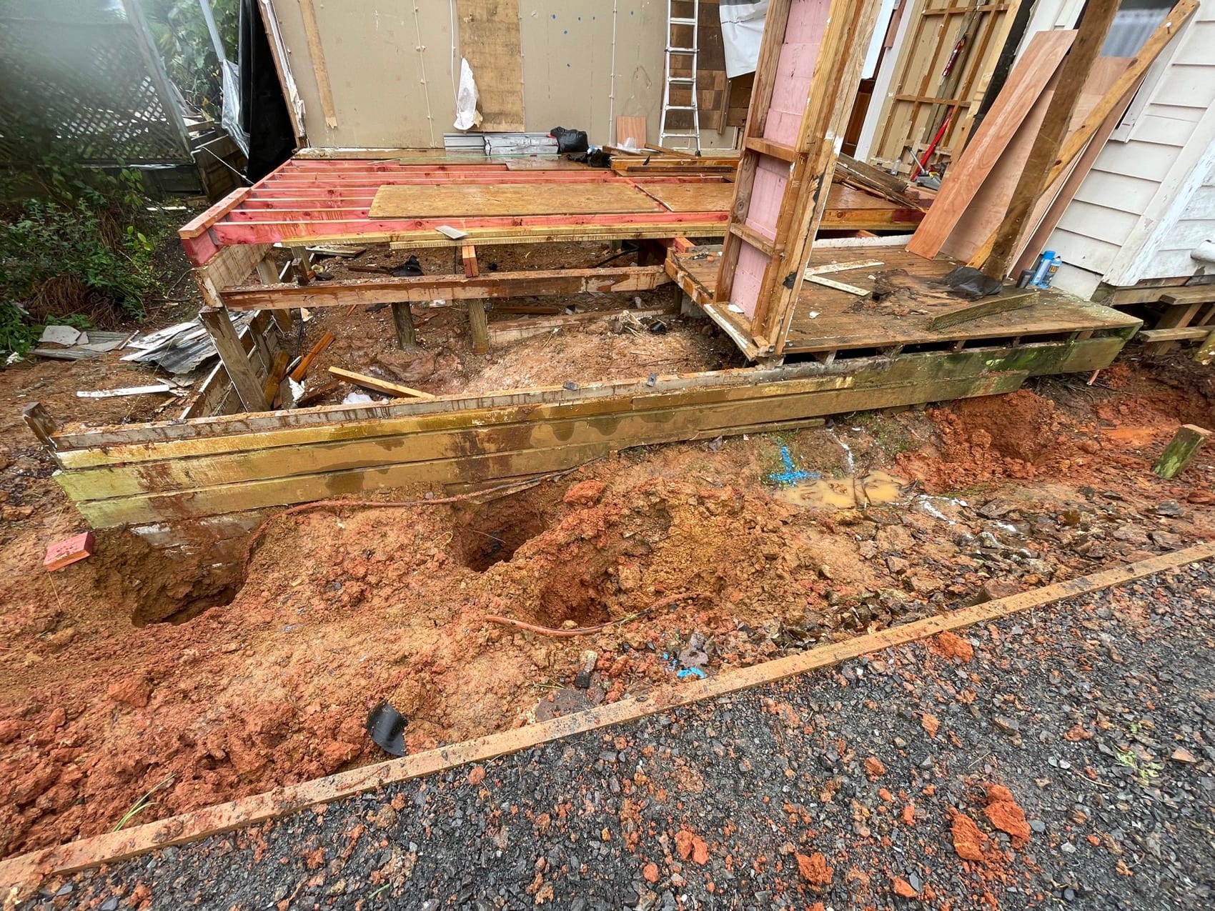 An old house propped and opened up underneath during re-piling, with new bearers going in.
