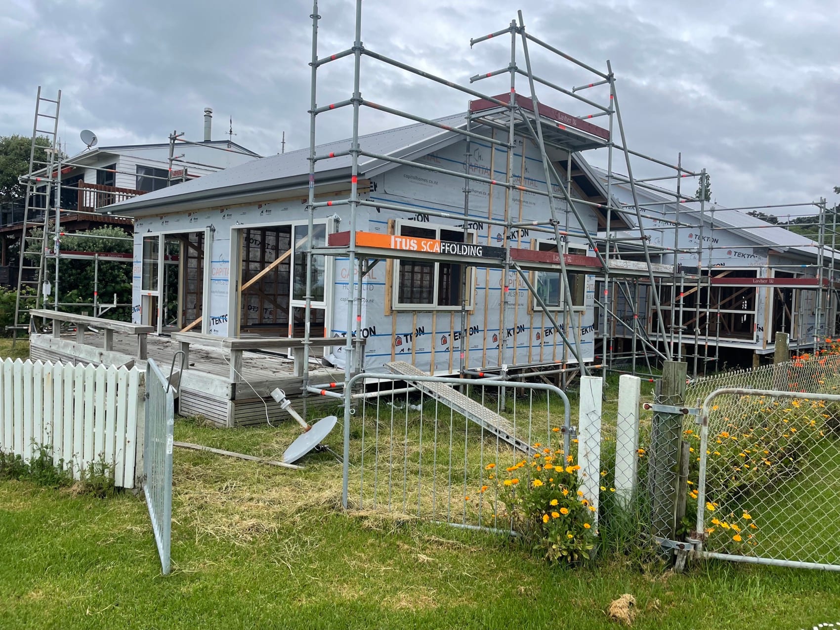 A house fully scaffolded and wrapped during a reclad, with new building wrap taped and window openings formed.