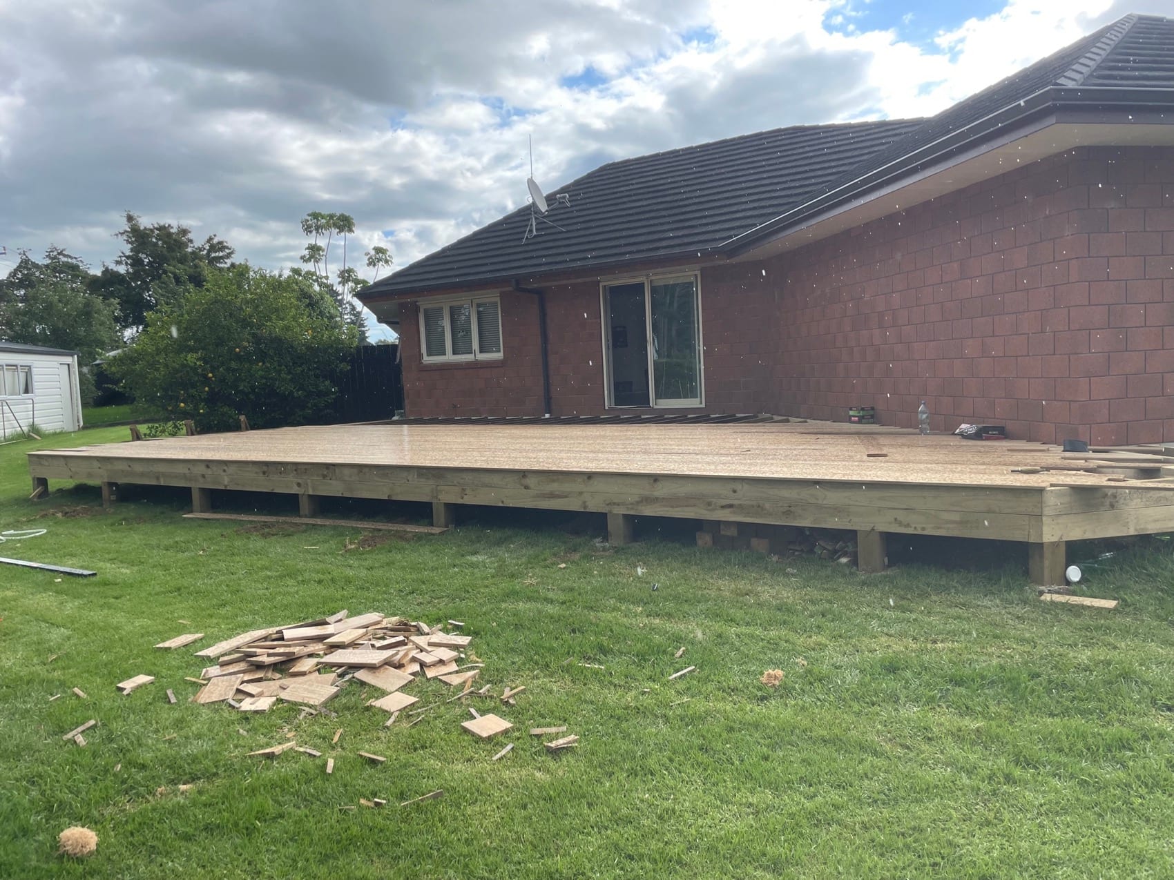 The same site before work started: bare lawn against the house with old pavers stacked to one side.