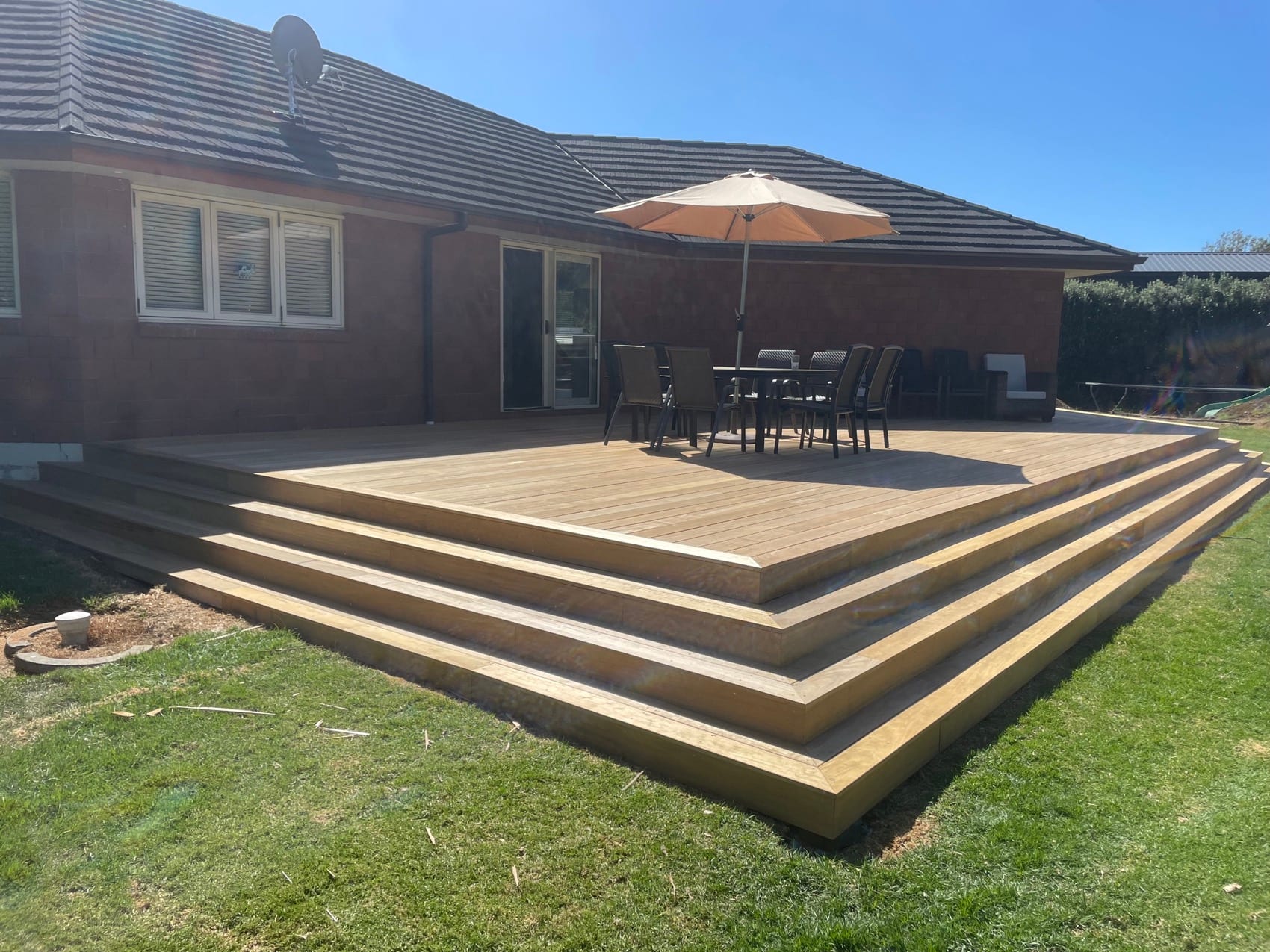 The completed deck and steps from the lawn, with outdoor furniture in place.