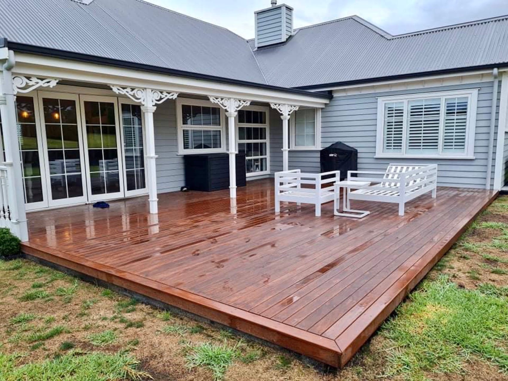 A stained timber deck wrapping a villa, furnished and finished.