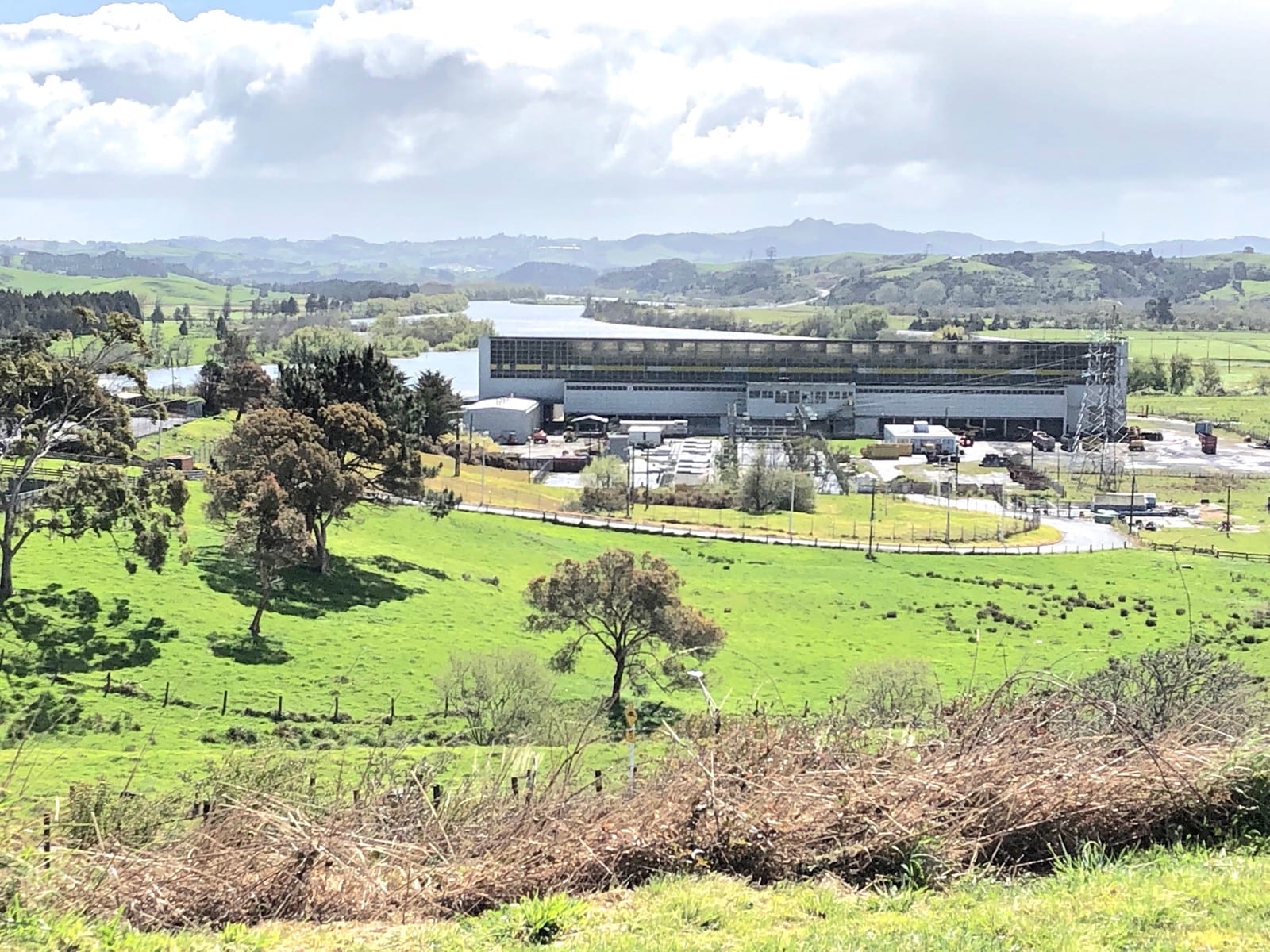 The former Meremere power station beside the Waikato River, framed by green farm paddocks.