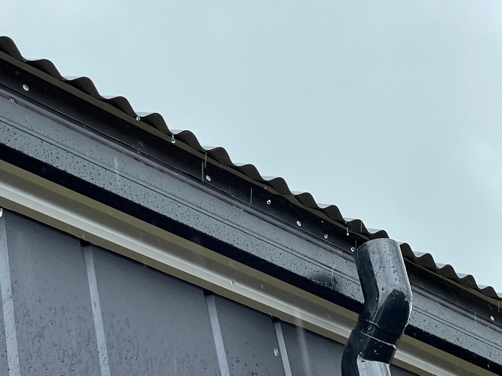 A corrugate roofline meeting dark vertical cladding.