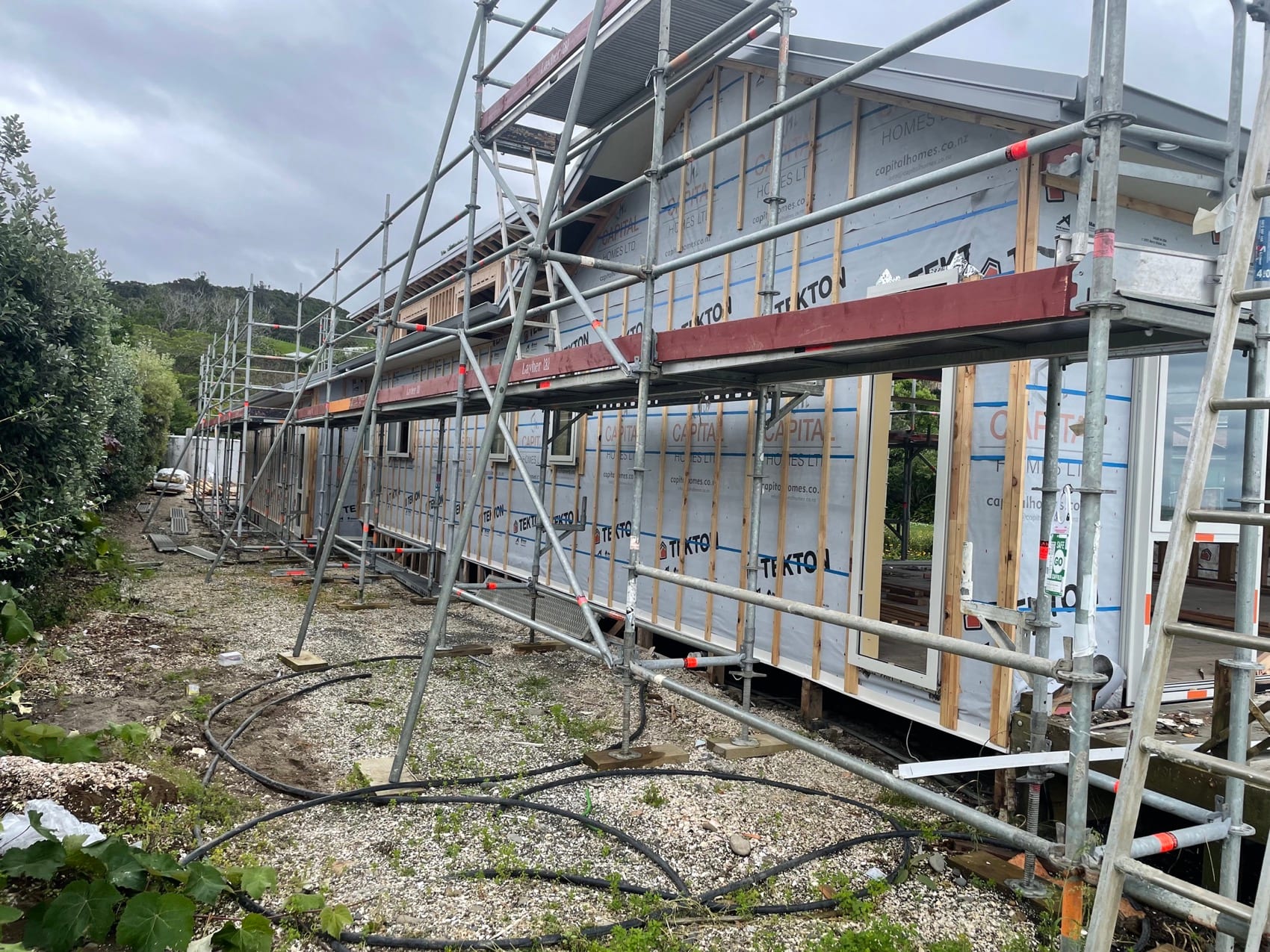 Scaffolding and building wrap down the side of a house part way through the build programme.