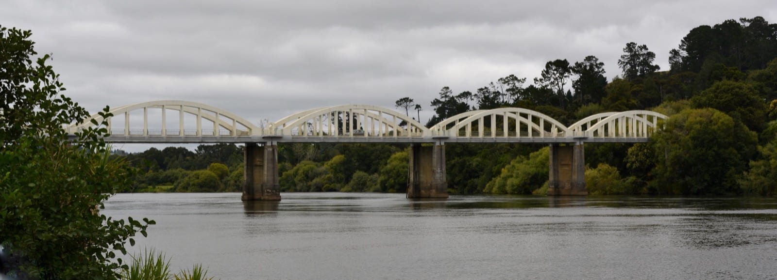 The white concrete arches of the Tuakau Bridge spanning the Waikato River.